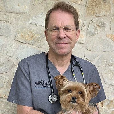dr. david hocher smiling and holding a small brown dog
